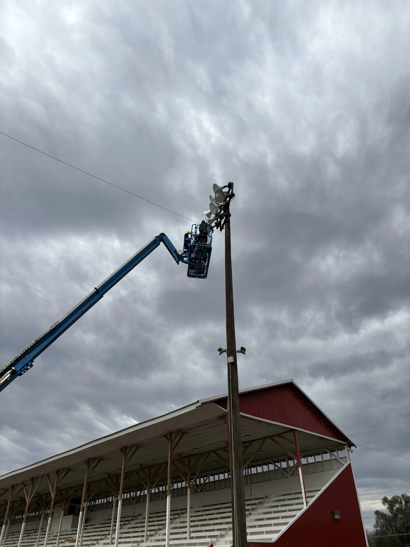 Electrician servicing high mast stadium floodlights from boom lift in Ontario, OR by Campbell Electric